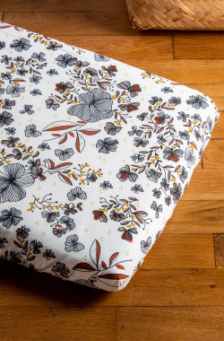 Drap contour Flora aux motifs floraux installé sur un matelas bébé, posé au sol sur un parquet